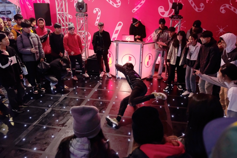 Crowd of youths circle around dance floor to watch a break-dancer 