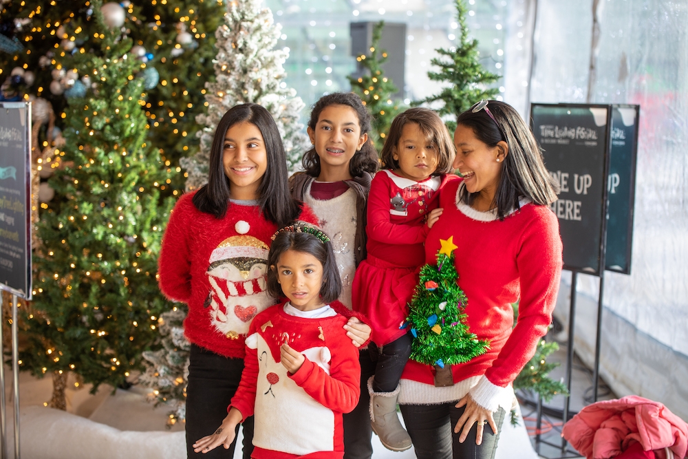 Family with mom and four girls all in red Christmas sweaters pose together